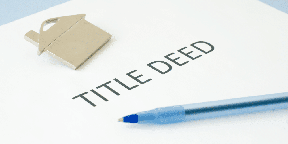 A title deed with a small model house and pen on it