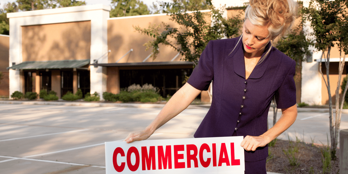 A commercial real estate agent placing a sign in front of a property